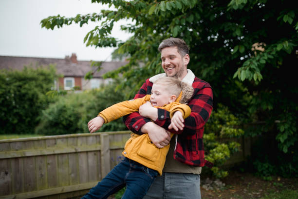 Father playfully swinging his laughing son outdoors
