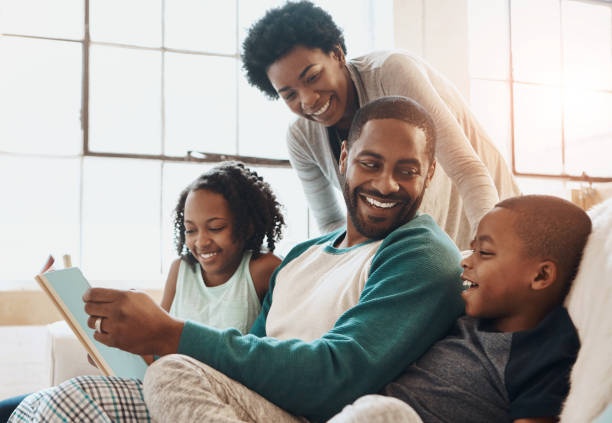 Family of four reading a book together on the sofa